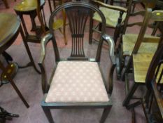 An antique mahogany elbow chair with a pierced splat back below an arched top rail, curved arms