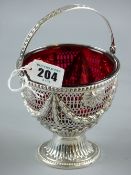 A Victorian silver swing handled sugar basket on pedestal base with cranberry glass liner, Sheffield