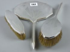 A hallmarked silver Art Deco three piece dressing table set of hand mirror and two brushes,