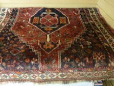 An Eastern woollen carpet with cream border, red ground central pattern with cobalt spandrels, 162 x