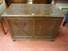 An early 20th Century carved oak lidded coffer, 64 cms high, 89 cms wide, 49.5 cms deep