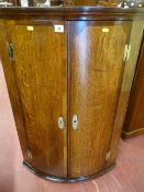 A Georgian oak and crossbanded mahogany bow front hanging corner cupboard with brass hinges and