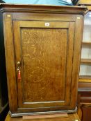 A Georgian oak single door hanging corner cupboard with brass knob and escutcheon with interior