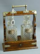 An oak two bottle tantalus with electroplate mounts and carrying handle enclosing two twist and