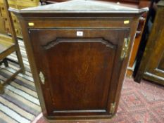 A 19th Century oak single door hanging corner cupboard with brass 'H' hinges and escutcheon,