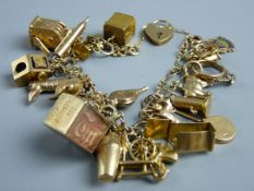 A NINE CARAT GOLD CHARM BRACELET with padlock clasp and over twenty charms including a one arm