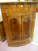 A VICTORIAN BOW FRONT HANGING CORNER CUPBOARD with inverted finial frieze decoration, twin raised