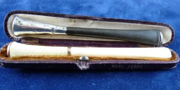 A CASED IVORY AND WHITE ENAMEL CIGARETTE HOLDER and an uncased ebony and silver cigarette holder