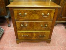 A NEAT MAHOGANY AND WALNUT THREE DRAWER CHEST, inset panel sides with shaped apron and corner