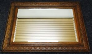 A LARGE OAK CARVED MIRROR WITH BEVELLED GLASS, 88 x 119cms