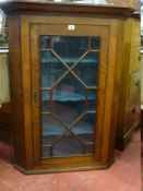 AN ANTIQUE OAK HANGING CORNER CUPBOARD having a single door with astragal panes