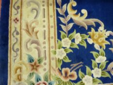 A LARGE BLUE GROUND WOOLLEN CARPET with wide cream border and central medallion of floral sprigs and