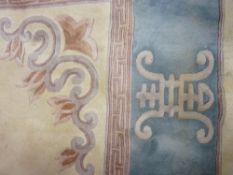 A LARGE CHINESE WASHED WOOLLEN CARPET on a cream ground with wide blue border and character mark