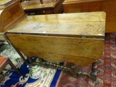 AN ANTIQUE OAK GATE LEG DINING TABLE with single flap and carved lower decoration with bobbin turned