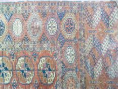 AN EASTERN RED GROUND WOOLLEN CARPET, wide bordered with central repeating block pattern, 305 x