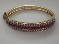 An 18ct yellow gold ruby and seed pearl bangle tha