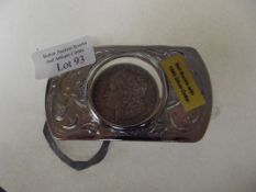 A belt buckle with an 1885 silver dollar