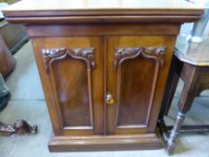 A Mahogany Cupboard, with decorative carving to arched panels, two internal drawers, raised on a