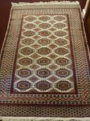 A Persian Style Carpet, with 24 central gul, with geometric border, claret design on cream ground,