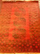 A 20th Century Afghan Burgundy/Black Woollen Rug, with three central gül and surrounded by a