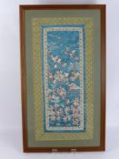A Pair of Chinese Silk Embroidered Panels, depicting many figures in a landscape setting, framed and