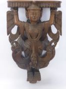 A Teak Siamese Wall Mounted Shelf, depicting a winged deity, approx 48 x 29 cms.