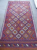 An Afghan Kilim Rug, with geometric design in orange, green, white and grey, approx 265 x 135 cms.