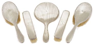 A silver five piece dressing table set with beaded and engine turned decoration, comprising two hair