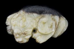 A two tone Chinese carved hardstone pendant the flat recumbent figure of a lion dog width 4.