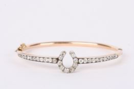 A delicate, early Edwardian diamond set horseshoe motif bangle, the upper half of the bangle mounted