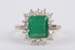 A Continental rectangular emerald and diamond set cluster ring the central step cut emerald