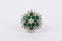 A 9ct white gold, emerald and diamond cluster ring the central diamond weighing 6pts, surrounded