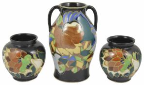 A large Gouda style twin handled vase decorated with stylised flowers and leaves against a black