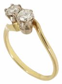 A delicate two stone diamond set cross over ring, yellow metal mount (tests gold). Stones approx.
