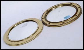 Two 20th century brass porthole style wall mirrors of circular form.