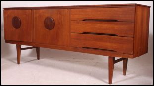 A 1970's retro teak Danish influence inverse bow front sideboard dresser being raised on tapered