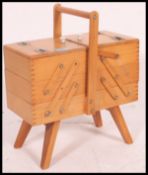 A vintage 1950's metamorphic sewing box with multiple hinged lid raised on tapered legs.
