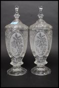 A pair of 20th century cut glass tall biscuit barrels, each to lids having finials tops.