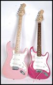 Two pink electric six string guitars,