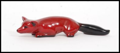 A Royal Doulton Flambe figure of a crouching fox, bold black and red colouring,