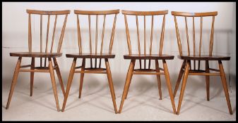 A set of 1970's retro Ercol beech and elm stick back dining chairs with panel seats raised on