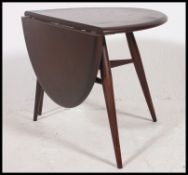 An Ercol retro 1970's drop leaf circular coffee - occasional table by Ercol raised on tapered legs