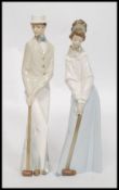 A pair of tall  Nao ceramic figures of a lady and a gentleman playing croquet being signed to the