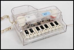 A retro 20th century novelty telephone in the form of a piano with working keys playing a tune when