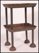 A mid century Industrial metal tote stand having two tray tiers on metal tubular frame with half