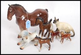 A collection of Beswick style figurines to include horses, Siamese cat, lamb,