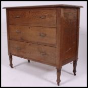 An early 20th century oak straight three chest of drawers, raised on stub legs.