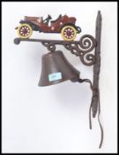 A 20th century cast metal wall hanging bell, decorated to top with a classic car.