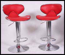 A pair of retro style red faux leather and chrome gas pump adjustable bar stools,