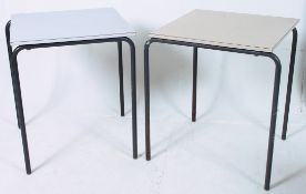 A pair of retro industrial school tables having a melamine top raised above metal tubular legs.